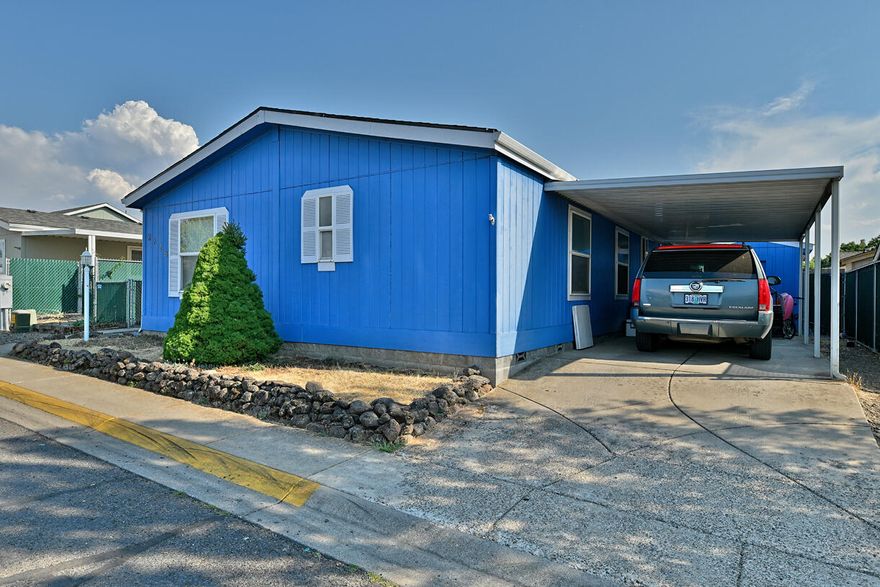 Very attractive and well-maintained manufactured home on its own lot in the desirable Hidden Grove neighborhood! Residents enjoy access to a private pool, clubhouse, basketball and tennis courts, all while being conveniently close to Central Point's city services and medical facilities. Inside, the home features an open kitchen with a charming semi-bayed breakfast nook, a separate dining area, and a spacious living room filled with natural light from large windows and vaulted ceilings. The split floor plan provides privacy for the master suite, while a generous laundry area offers direct access to the rear porch. Outdoor storage is plentiful with a wooden shed in the carport and an additional garden shed in the backyard.