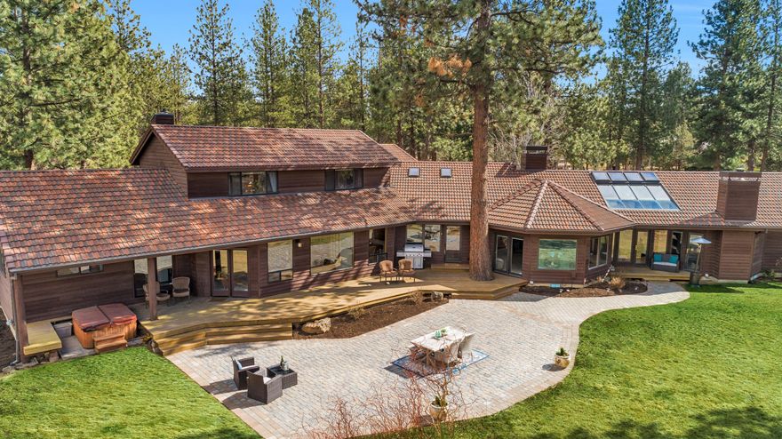 Spacious custom home on nearly 15 acres with end-of-road gated privacy, in a quiet park like setting. At nearly 4,500 sf and featuring two main level master suites, this home has room for all. Warm and inviting with log accents, solid wood doors, Brazilian cherry floors and large windows that offer an abundance of natural light throughout. The kitchen features granite countertops, custom built-ins and a large island that overlooks the vaulted great room with a rock fireplace. As you walk through the solarium and enter the primary master suite you feel a true sense of privacy and serenity. This suite features his and hers walk in closets, fireplace and a spacious bathroom with a claw foot soaking tub. Outside you'll love the large deck and paver patio that is perfect for summertime games, relaxing and entertaining. Additionally, the property is fenced and cross fenced with a 3-stall barn, 7 acres of irrigation rights and just a stone's throw away to the Deschutes National Forest.