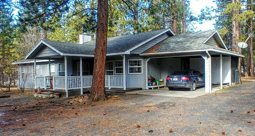 Charming home with fenced 1 acre on quiet Riverwoods Dr.  Walk on to the covered front porch and into this roomy 1719 sqft 2 bedroom 2 bath home. The spacious, flexible living area features a wood stove and sliding door to the huge back deck.  The kitchen is generously sized and bright with space for eating in or extra storage.  The main bedroom includes a bath with large double vanity, enclosed shower and toilet, and double closets.  Great parking is available with a carport and storage right off the utility room and a detached double garage with an extra full bath and awesome workbench area.  The fully fenced property also has a RV full hook up box, covered firewood storage and other storage sheds, and drive through gates. This peaceful home sits back from the street on a pretty, naturally landscaped lot but not far from Bend's shopping and businesses. Lots of potential to make it your own close in country retreat!