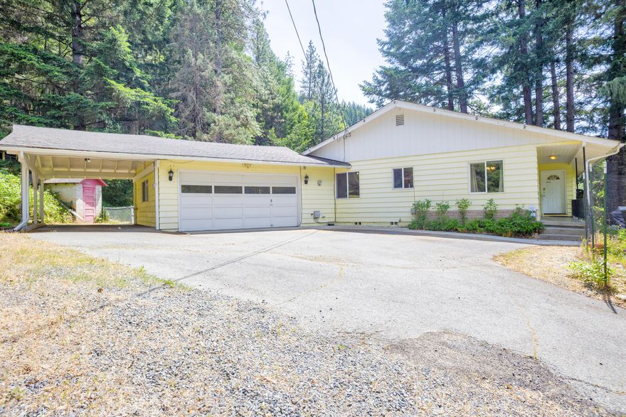 Unique riverfront property on just over 1-acre with tons of potential! This 2 bed, 2 bath, 1,422 sqft home is full of character and ready for your vision. Original hardwood floors, a large gas fireplace, river views, and a versatile sunroom are just a few of the standout features. The home was previously used as an Airbnb and would make a great vacation rental. The attached 2-car garage, carport, and RV parking with hookups provide plenty of space to park multiple vehicles. Directly across the street is your own private river frontage to enjoy the beauty of the mighty Rogue.