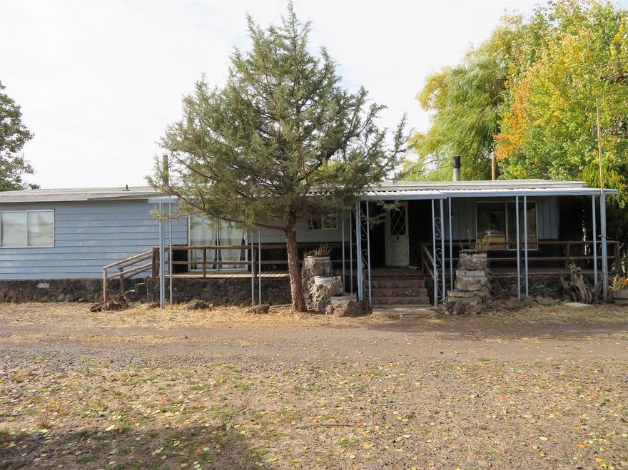 This 1975 manufactured home sits on 2.4 acres that includes a fenced pasture along with stalls, tack room and storage room just waiting for your horses. Separate pens for FFA/4-H projects and for rover, some kennels. You'll find plenty of space for your on and off-road vehicles with 2 carports and a circular driveway. A variety of large trees provide lots of shade and privacy for outdoor entertaining with plenty of room for fun. The home is 1584 square feet and is a roomy 2 bedroom/2 bath with plenty of storage, including extra-large closets and master bath with big corner tub. A built-in buffet, wet bar, cold-storage room and custom rustic touches are a few extras. The certified wood stove will add heat and coziness this winter. It has a covered front porch and a handy enclosed back porch. Pumphouse repaired 4 years ago has a heat lamp and storage space.
