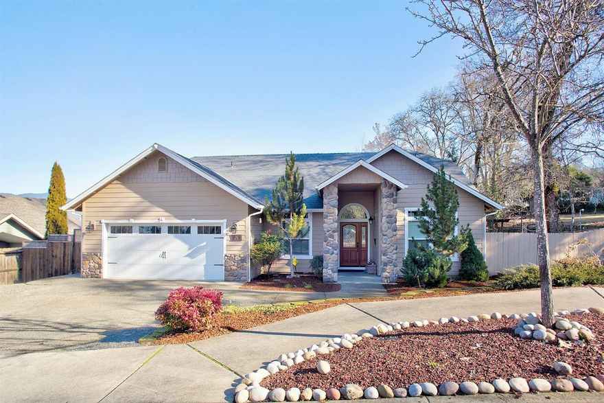 A beautiful Kirk Chapman-built home on a quiet street with a grand entry adorned with rock columns & flanked with gorgeous low-maintenance landscaping. Through the door is an impressive open great room with gas fireplace, raised & vaulted ceilings, hardwood floors & granite counters. A bevy of windows allow plenty of light & offer mountain views. The spacious, granite island, breakfast bar kitchen with custom wood cabinets & stainless steel appliances has plenty of counter space to prepare any gourmet meal. Step through the slider to the covered rear patio to enjoy the peaceful afternoon shade. The large Master Bedroom with ample walk-in closet & bath includes a separate patio with hot tub. On the side is a garden area that could easily be converted into plenty of RV parking. The trailhead to Cathedral Hills with miles of lush trails is just up the road. Country feel, yet with District 7 schools, close to shopping & just minutes from The Mighty Rogue River! Call for a look inside today