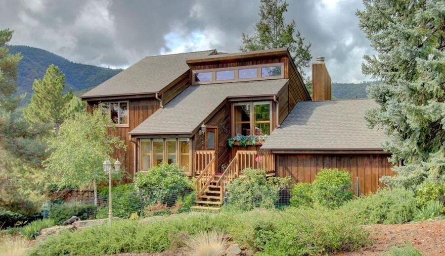 Beautiful Ashland Contemporary View property. This unique, architecturally designed home overlooks the Siskiyous, Wrights Creek and Medford lights, and features an open, vaulted plan, large windows, miles of hardwood flooring, warm wood walls, cozy fireplace, lots of built-ins and big decks overlooking the gorgeous half acre lot. The spacious living room opens nicely to the dining area, well appointed kitchen and over-sized sun room. The main-level master suite includes vaulted ceiling, built-in media cabinetry, large closet spaces and custom designed bath. Upstairs are two spacious guest bedrooms, Jack-and-Jill bath, viewing gallery and a cozy reading loft. There's plenty of storage on the lower level, and the lovingly landscaped grounds are accented by mature specimen trees, flowering plants, raised beds and lovely walkway. The large, view lot may accommodate an Accessory Dwelling Unit, please check with the City. A great home in a wonderful Ashland neighborhood!