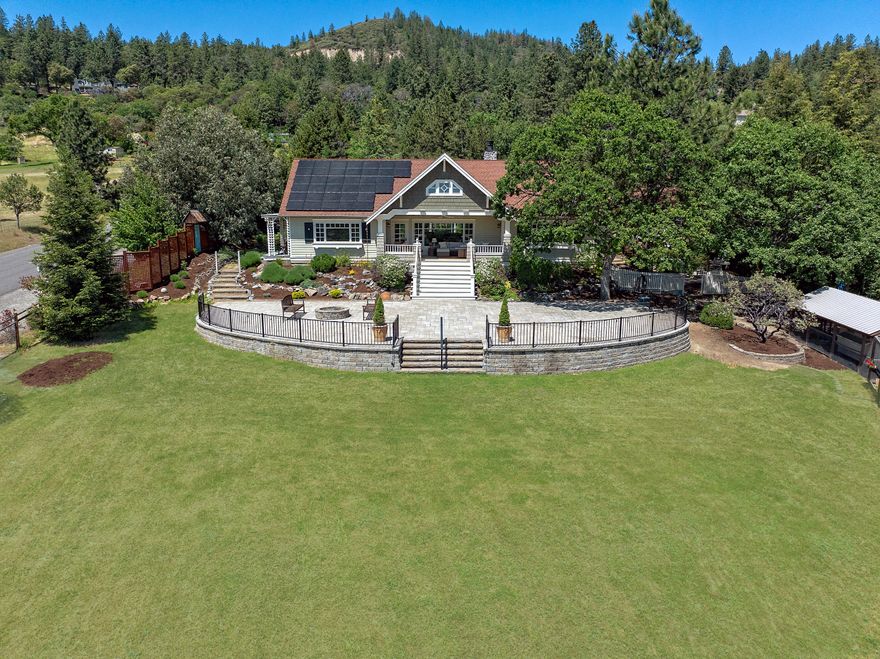 Enjoy the breathtaking mountain vistas and pastoral vineyards from this meticulously crafted custom home, nestled above the valley on the highly sought-after Tami Lane. This 1.74-acre private countryside home is located 5 minutes from Historic Jacksonville. Experience superior craftsmanship in this single-level residence with hardwood floors, a grand great room boasting vaulted wood ceilings, an artisanal stone fireplace and breathtaking views. Retreat to one of two primary suites, each featuring walk-in closets and full bathrooms for ultimate comfort and privacy. The kitchen boasts a commercial-style 6-burner range/oven and built-in refrigerator for culinary enthusiasts. Outdoor entertaining is a delight with multiple spaces, including a covered porch, two patios and a firepit. Additional features include detached guest quarters, a two-car garage with workbenches, attic storage, RV parking with hook-ups, and solar power with a generator outlet. Don't wait to show this stunning home.