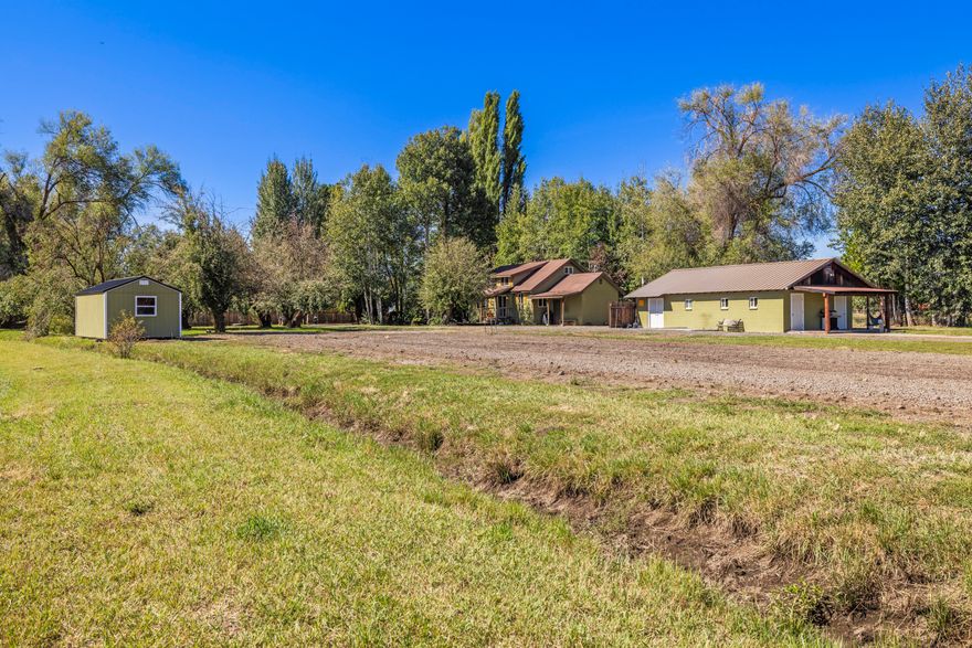 Dreaming of wide-open space with endless possibilities? This charming farmstead delivers. 11.43 acres of lush pasture with water rights and simple flood irrigation keep your land green and productive. The cottage-style farmhouse is full of warmth with barn wood accents, while the fully finished milk parlor has been transformed into a 1-bed, 1-bath guest home—perfect for rental income or multi-gen living. The century-old barn is a showstopper—paved floors, loft, tack room, stalls, and paddocks, all brimming with character. Fully fenced for privacy, plus an orchard and charming landscaping. Ready to be your working farm, private oasis, or unforgettable event venue.