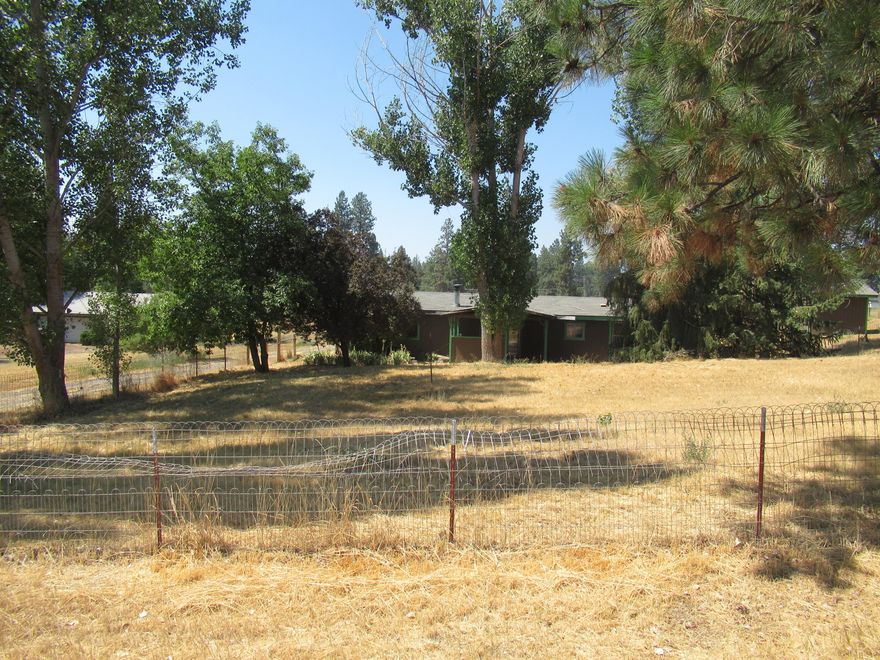 This is a lovely 1982 manufactured home on 1 acre. 2 Primary bedrooms, both with full baths. This home offers open living space with ample sunlight. Move-in-ready condition. The front yard is fenced with a private front porch, garden area, and multiple mature trees for relaxing in the summer breeze and shade. The garage has been converted into a large workshop with plenty of storage for all your goodies, crafts, & hobbies. The heating unit and the air conditioner have been recently serviced.
The entire property has been spruced up and a professional cleaning service has polished the inside to perfection. This home has vinyl throughout, there is no carpet for a clean fresh ambiance.  All appliances stay with this home.  Affordability & Comfort await you.  *Call today for your private showing.