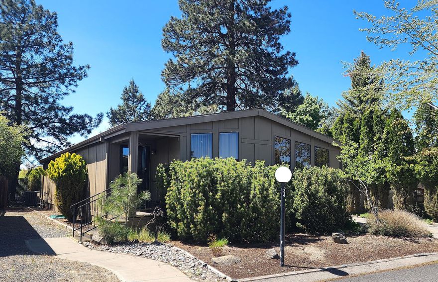 Affordable home in 55+ Suntree Village Park with Cascade Mountain VIEWS! Located in a quiet area at the back of the park, this home boasts a NEW furnace and heat pump in 2025, new exterior paint in 2023, fenced back yard with two-tier deck, and deep, attached carport. This comfortable home has an efficient floor plan with good-sized rooms. Large kitchen with extensive counter tops/cabinetry and double oven. Living room with vaulted ceiling and lots of light. Relish the beautiful mountain views from the primary bedroom and back deck. Enjoy the built-in radio with speakers in Primary BR, Living Room and Dining Area. This home is dated and needs some TLC. It is waiting for your special touches and priced accordingly! Home is being sold AS-IS.  Space rent is $599/month and includes water/sewer/garbage/clubhouse/street snow removal and debris pickup. Come check out this great home!