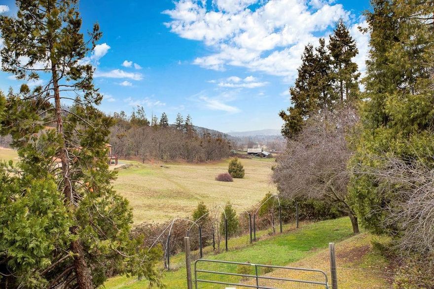 Nestled in Talent's serene countryside, this meticulously maintained home is a haven of natural light. With soaring vaulted ceilings in the main living area, expansive picture windows, and a deck offering breathtaking views, this residence welcomes the beauty of the outdoors. The open-concept kitchen features tiled floors/counters, oak cabinetry, and stainless appliances. The vaulted master bedroom, alongside the guest bedroom, boasts stunning views of Wagner Butte. The bathroom w/ accessibility to one of the bedrooms features a double vanity and walk-in shower. Heading downstairs, discover a versatile bonus area suitable for a 3rd bedroom or office. The lower level surprises w/ an oversized garage conversion, potentially a 4th bedroom, hobby room, or rec space, w/ a separate entrance. Behind this space, find a spacious single garage w/ addtl shop area. The charming grounds include majestic cedars, fruit trees, mature plantings, and a zen-inspired front yard w/ a new composite deck.