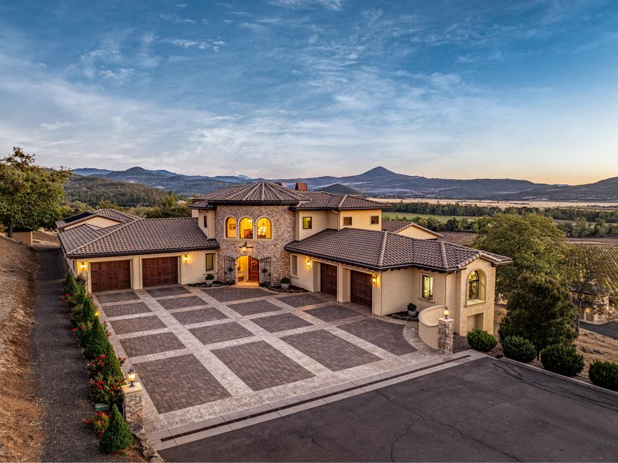 Surrounded by the natural beauty of Southern Oregon's Rogue Valley, this Mediterranean-inspired estate pairs timeless design with agricultural excellence. The 7,256± sq. ft. residence centers around a private courtyard and showcases cathedral ceilings, a grand entry, and a chef's kitchen opening to a grand great room and multiple outdoor living areas. The primary suite offers vineyard views, spa-style bath, and expansive deck, while amenities include an executive office, library, wine room, gym, sauna, and indoor saltwater pool. A matching 851± sq. ft. casita provides a luxurious one-bedroom guest retreat overlooking the vines. The 160-acre property features Celtic Moon Vineyards—42.5± acres of premium vines with 77.44 acres of irrigation rights. Located minutes from Eagle Point and Medford, this private estate captures the essence of Southern Oregon's wine country lifestyle.
