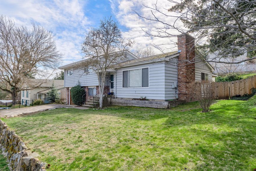 This above the boulevard home is situated on a spacious corner lot across from the upper side of Asante Ashland Community Hospital and within close distance to downtown Ashland. The main living space has a nice open living/dining room with views, fireplace, sunny kitchen with tile floor, three bedrooms & 2 baths. The lower level services the laundry area, extra storage room and a one-car garage.  Wonderful spacious-fenced and landscaped backyard, a covered patio and plenty of room for gardening and play.  Additional off-street parking available on the paved parking pad adjacent to the attached garage.