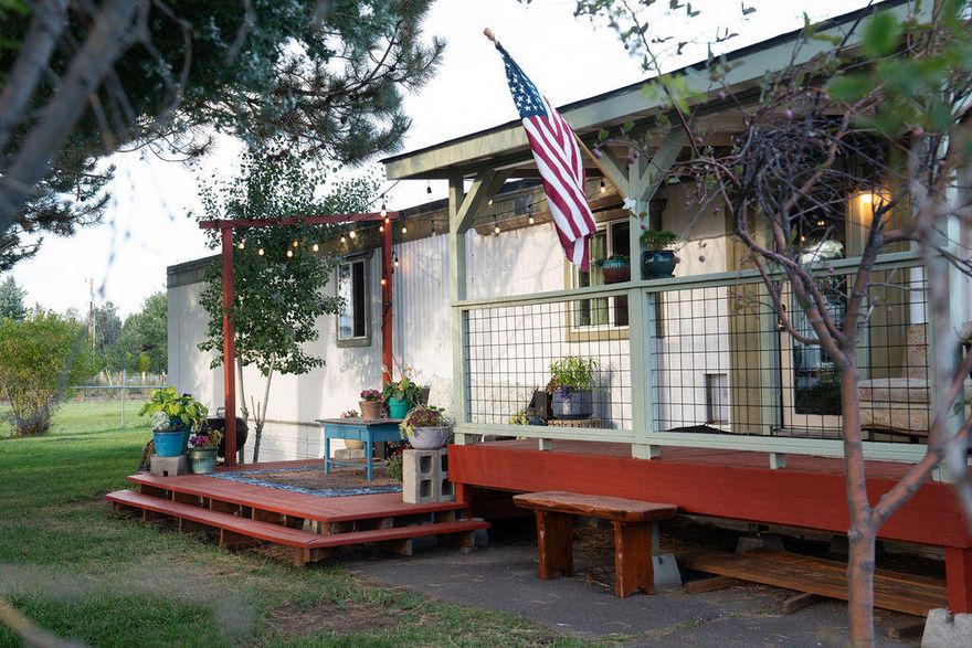 Welcome to this charming, well-maintained manufactured home tucked away in a peaceful park community. Situated on a corner lot that faces a pasture with only one neighboring lot, this single-wide has kickouts, providing a bright, open-concept floor plan that's perfect for relaxing or entertaining. The kitchen layout is functional with ample counter space and storage. The two bedrooms are at opposing ends of the home, offering desirable separation—ideal for a small family, guests, or a home office. Other features include indoor laundry hookups, a portable A/C, and built-in storage in one bedroom. Outside, you will find a beautiful new deck at the front porch, established landscaping, and a fenced yard—perfect for quiet mornings with coffee, evenings under the stars, and plenty of room for pets or a garden. Plus, enjoy convenient access to Tumalo and the 97!