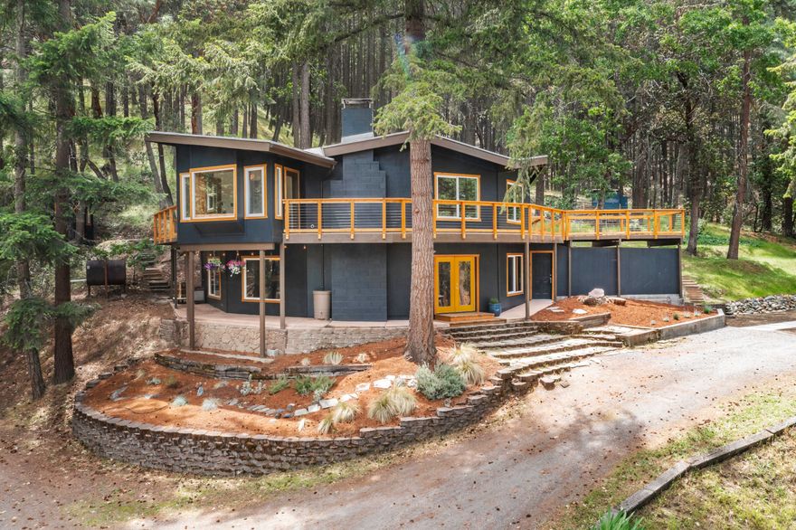 Situated on nearly 2 acres among the trees, this unique & tranquil home sits in the hills above Ashland and is truly one-of-a-kind. Loads of natural light & a wrap-around cedar deck, come enjoy the quiet peace of the forest & be only a short distance to shopping & restaurants. Upper level has full kitchen w/cherry cabinets, stone flooring & granite counters w/3 -seat brkfast bar. Bright sunroom off kitchen w/window seating perfect for morning tea.  Living area w/fp & walls of windows looking into the forest. 3 spacious bdrms & 2 full baths including primary with en suite & access to sauna. Lower level features a great room w/wood burning stove, & full bath w/tub/shower combo. Separate entrance to additional living space w/short-term rental history (or use as 4th bdrm).  It features a lofted full-sized bed, sitting area, & full bath. Outdoor area perfect for entertaining!