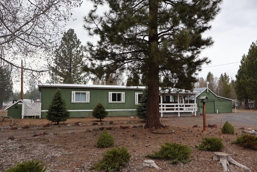 This is a 2 bedroom and 2 bath manufactured home, built in 1974 with a total area of 1056 sq. ft. It is located on a cul-de-sac within the Jack Pine Village subdivision, sitting on a spacious 2.24-acre lot. The home is equipped with a certified woodstove, oil heat monitor, and a heat pump. There's an addition off of the kitchen that would be perfect for a hobby room with a built-in pantry. Additionally, there's an enclosed back porch and a covered front porch. You'll also find a garden shed with a little greenhouse to grow your own veggies. There are several storage buildings, including a woodshed, and a fenced backyard.