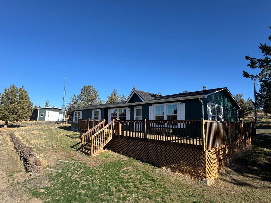 Extremely peaceful & private country setting offering stunning sunsets just minutes from Prineville! Discover a perfect blend of comfort, privacy, & practicality in this well-maintained home sitting on 10 fenced low-maintenance acres. Fresh interior & exterior paint, new hot water heater, & brand-new roof means all the hard work is done—just move in & enjoy! Step inside to find vaulted ceilings, hardwood floors, all appliances included, & a spacious kitchen w/ample storage and island seating—ideal for entertaining or everyday living. Large windows frame the beautiful views, while the wraparound deck invites you to relax & soak in the serene, tree-studded surroundings. Bring your hobbies & projects—this property features multiple outbuildings, including a great versatile shop w/concrete floors, & detached garage. Enjoy peace, privacy, & room to roam. The included 5-acre parcel to the West is a separate tax lot & is buildable, perfect for family compounds or a bonus investment property