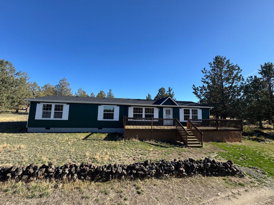 Extremely peaceful & private country setting offering stunning sunsets just minutes from Prineville! Discover a perfect blend of comfort, privacy, & practicality in this well-maintained home sitting on 10 fenced low-maintenance acres. Fresh interior & exterior paint, new hot water heater, & brand-new roof means all the hard work is done—just move in & enjoy! Step inside to find vaulted ceilings, hardwood floors, all appliances included, & a spacious kitchen w/ample storage and island seating—ideal for entertaining or everyday living. Large windows frame the beautiful views, while the wraparound deck invites you to relax & soak in the serene, tree-studded surroundings. Bring your hobbies & projects—this property features multiple outbuildings, including a great versatile shop w/concrete floors, & detached garage. Enjoy peace, privacy, & room to roam. The included 5-acre parcel to the West is a separate tax lot & is buildable, perfect for family compounds or a bonus investment property