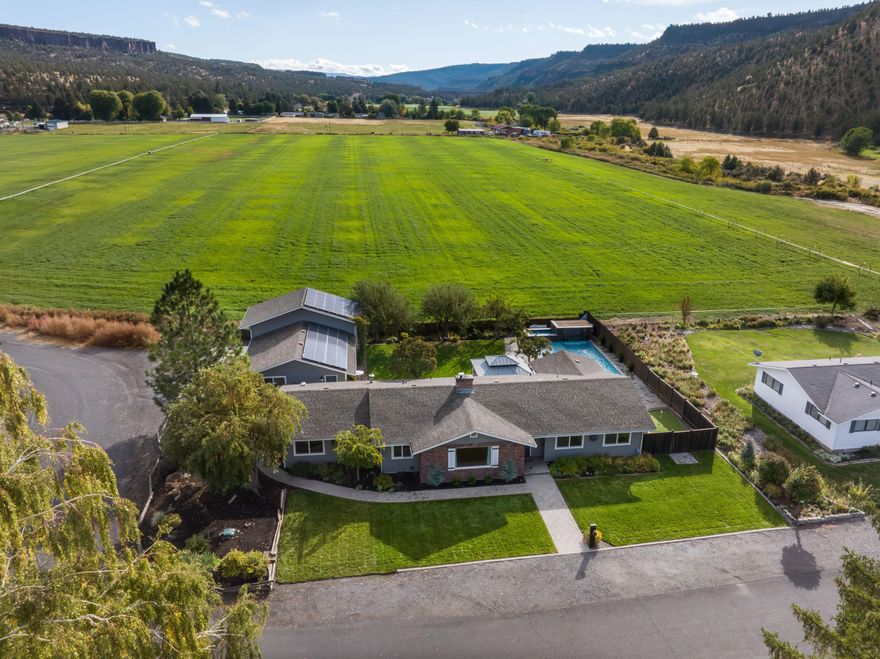 Stunning single level country home near Prineville Golf Club, featuring a saltwater pool and spa. Fully remodeled, this 2,136 sq ft home features 4 bedrooms, 3 bathrooms, and a cozy living room with a stone wood-burning stove. The chef's kitchen shines with a breakfast bar/island, solid surface countertops, pantry, and adjacent dining area with patio access. The primary suite offers a tiled shower, built in cabinets and walk-in closet. Enjoy a beautifully landscaped, private backyard with a pool with swim jet, spa, gazebo, patio, mature fruit trees, and scenic views of farmland and valley rimrock. Includes a 3 car garage with an RV bay and a 10 KW grid-connected solar system (owned). Nestled in a peaceful neighborhood on Prineville's east side, close to the semi-private 9-hole Prineville Golf and Country Club with a dual tee system, and just minutes from town, the Ochoco Mountains, and Ochoco Reservoir.