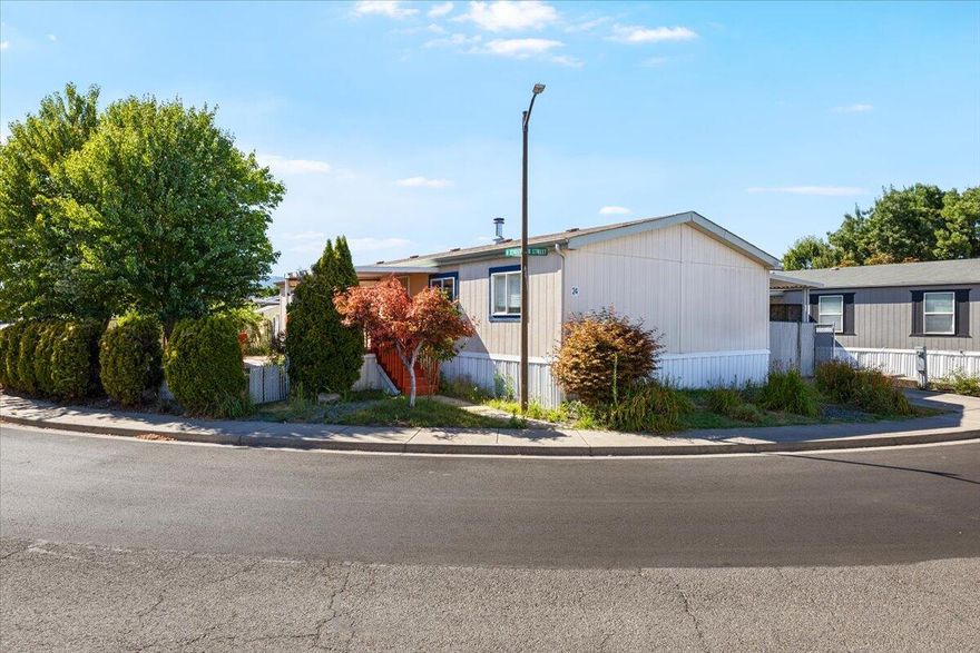 Welcome to Meadow View Estates! This charming in-park manufactured home sits on a desirable corner lot w/ mature landscaping, a grape arbor, and a peach tree. Enjoy the spacious front deck, partially covered for year-round relaxation or unwind in the side yard under the pergola. Inside, the split floor plan offers privacy, w/ the master suite located off the family room. The master features an ensuite w/ a walk-in closet for plenty of storage. Vaulted ceilings and a wood-burning stove create a warm, inviting atmosphere. The open-concept kitchen boasts stain-grade cabinets, a pantry, and new refrigerator, flowing seamlessly into the dining area. Off the kitchen, the laundry/mud room w/ new washer and dryer leads to the back deck and attached carport for easy access. Additional features include fresh paint updates, updated flooring in the guest bath, and a storage shed. This home offers generous outdoor space and a thoughtful layout, making it a comfortable and charming place to live.