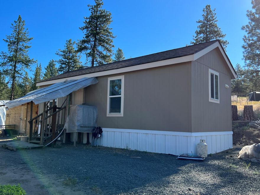 Looking for an off-grid lifestyle?!?  Here is a property all set up for just that.  Almost 4 acres with approved well and septic. Well dug in 2017, new pump in 2022. Power is available at the road, but this property is set up to be fully ran with generators, one is being left with property! Small, 1 bed/1 bath single wide manufactured home, freshly painted! 10x12 outdoor kitchen, which includes refrigerator, chest freezer, and camp stove,  3 greenhouses, travel trailer, storage container, water holding tanks and storage sheds are some of the features that make up this unique property. Buyer to do their own due diligence. Possible owner carry with 50% down.