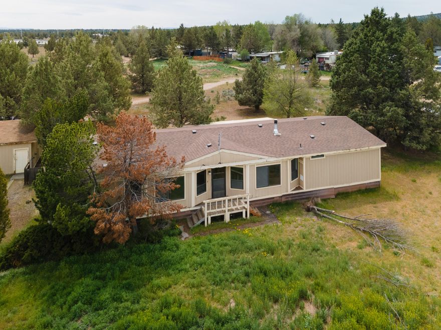 Opportunities abound at this 2.14 acre property on a private airstrip located right across the highway from Eagle Crest in beautiful Redmond, OR! Fly directly into town and park in the 1600 sq. ft. hangar located at the end of the runway. The 1983 manufactured home and it's 1782 sq. ft. floorplan is functional and spacious. With a separation between the guest bedrooms and the primary, it offers privacy, beaming natural light and a ton of open space. The large open kitchen has plenty of storage and comes complete with a fridge (washer and dryer are also included). Home has central heat and air, along with a woodstove. In addition to the huge hangar, there is also a 2 car detached garage giving you ample parking and/or storage. Live in the home or build your own dream house.