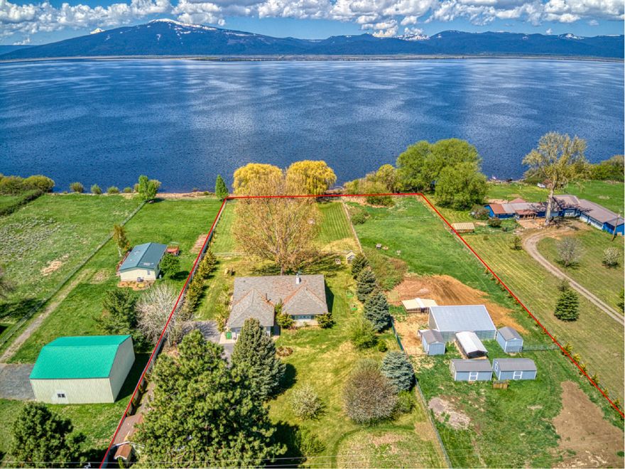Gorgeous lakefront property! Wildlife lovers paradise! 2.75 acres, 2 contiguous lots with potential to sell separately including  250 ft. of Agency Lake frontage, Private sandy beach. Space for garden & animals. 2001 Nicely appointed home. 2,294 sq. ft., 3 bedroom 3 bath single level home. Carpet/vinyl/tile; New appliances in 2022 washer, dryer. jetted tub; propane fireplace; bay windows; storage; covered porch. Walls of windows year-round views of lake, mountains. 2 car garage. Central Air/Heat Pump/Oil/Propane/Electric. Generator ready. 2nd Garage/Workshop with roll-up doors/220 outlets/storage,12X14 bonus room. Air compressor plumbing. Custom Solar Greenhouse 8X12.  Private well for  household use, lawn/garden irrigation and farm animals. Zoned Rural Residential-2. Dryland pastures. Barn, Newer custom shelters on skids negotiable with an acceptable offer Prolific fruit trees. Raised garden beds. Cross fenced, gated. No pesticides used. This home is move-in ready and priced to sell