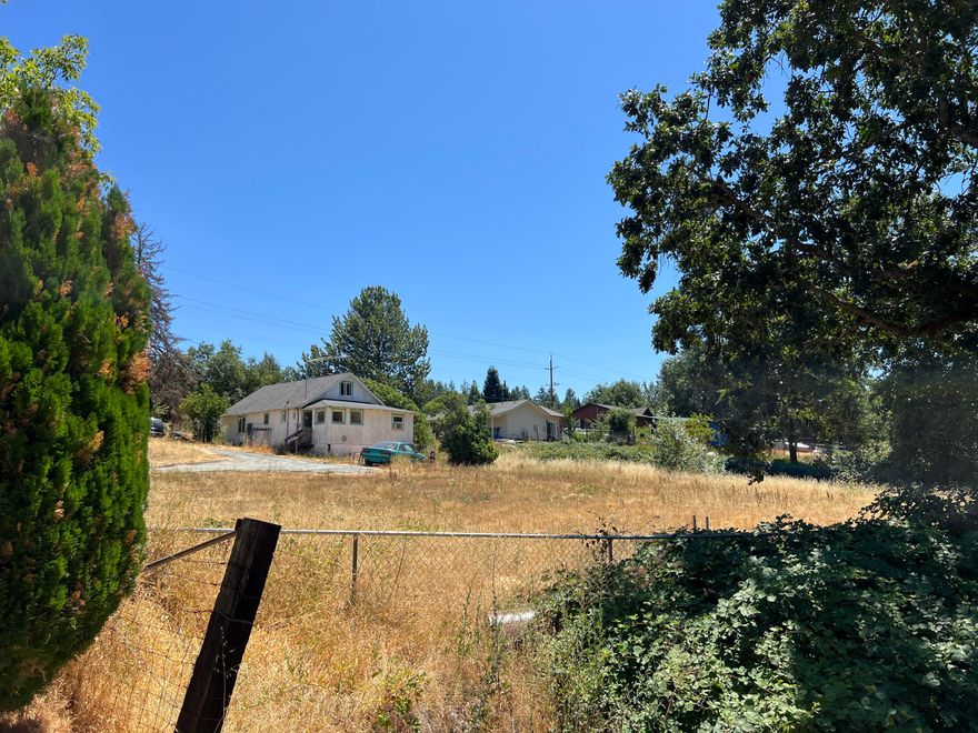 Attention builder/developers. Welcome to this prime 1.29-acre development opportunity on the edge of town. This flat, usable land offers the perfect canvas for your next residential project and may facilitate up to 6 building lots for new homes. The existing 1950 structure could possibly be refurbished or demolished. Utilities nearby and should be efficient to connect. Enjoy a serene, rural feel with these potential future new homes, while still being conveniently close to Asante Medical Center, parks, golf courses, vineyards, shopping, schools and recreation. Don't miss out on this rare chance to shape your vision in a growing area. Buyer to perform due diligence in regard to potential for development.