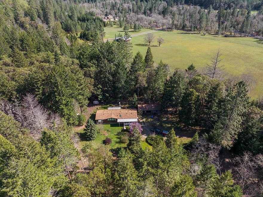 Peaceful & Private Off-Road setting for this Lovely Home on 6.59 Acres in the Desirable Jumpoff Joe Creek Road Area! This Property Offers a 3 Bed, 2 Bath, 1,716 Sq Ft Home, Detached Two-Car Garage with Workshop area, Barn with Upstairs Man Cave, & Detached Carport, all w/power, plus several Smaller Outbuildings. The Well-Kept Home features a Country Kitchen with skylight, Granite Counters & Large Pantry. A beautiful Living room w/vaulted ceiling & bay windows, plus Family room w/woodstove that features a nice dining area! Large Master Suite features Dual Vanities, lovely soaking tub, plus a shower & Walk-in Closet. Nice Guest Bedrooms, one with walk-in closet, & a Guest Bath with Shower/Tub combo. Multiple storage closets, plus second walk-in pantry. Huge Laundry room with room for freezer. Great Storage Sheds & Multi-Use Buildings. Covered decks Front & Rear. Useable Land, Fenced Garden area, beautiful trees & Plenty of room for Animals. Privacy with a quiet Country Setting!