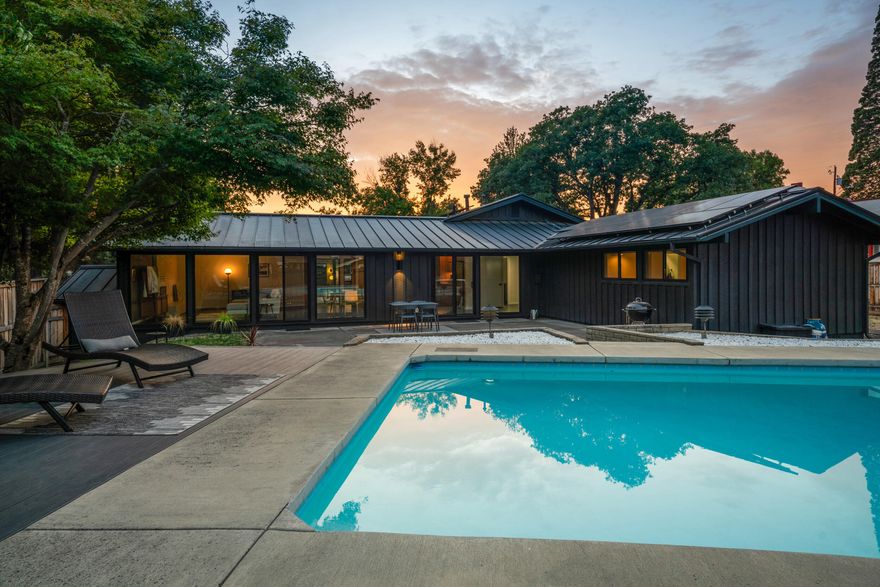 Lovingly restored to its mid-century glory, this 4-bedroom, 2-bath Cliff May designed home blends iconic style with thoughtful modern updates. Known as the creator of the California Ranch, May's designs are celebrated for their open layouts, natural light, and seamless indoor/outdoor living- perfectly captured here with double sliders that connect the spacious living area to the backyard. The sparkling concrete-and-tile pool with a UV filter and evening lighting sets the scene for unforgettable summer nights, while a recent interior remodel highlights the home's timeless character with modern finishes. Recent exterior paint, a low-maintenance metal roof, and paid-for solar panels with an EV charging station deliver exceptional cost efficiency and sustainable living. All this in desirable Old East Medford, right next to Holmes Park-  a rare chance to own a piece of MCM architecture with today's conveniences.
