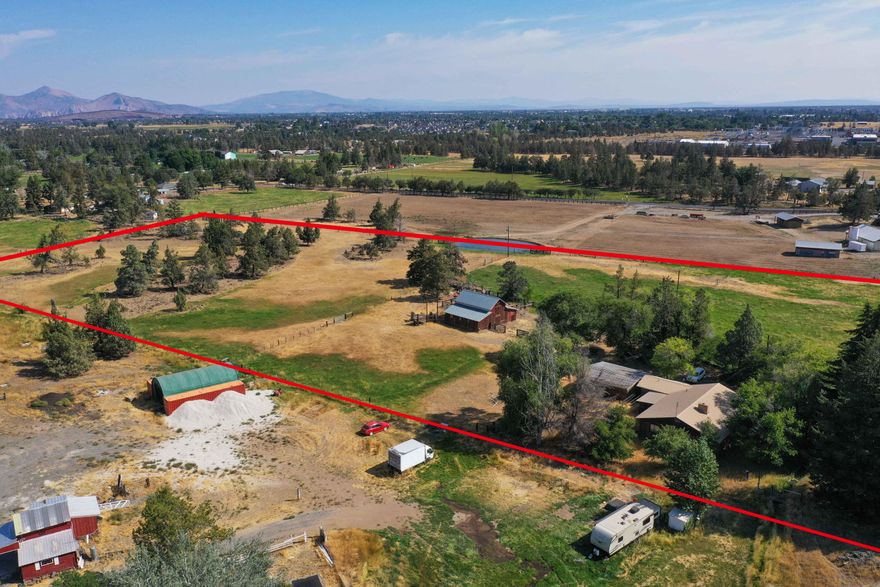 Amazing fixer opportunity! Have you always wanted to own your very own farm close to town? Now is your chance to make that dream a reality. This expansive 9 acre parcel has amazing potential to be an oasis with a spacious single level home, large barn, and 6 acres of irrigation rights on a mostly flat lot. The flowing ranch style home has large living areas, a primary bedroom and two large additional bedrooms, huge laundry/mud room, and two guest bathrooms. Steps away is a detached oversized 2-car garage with workshop space. The property features a large barn with stables, fenced pasture areas, and endless possibilities. Property is being sold AS IS.  Needs new well for drinking water or possibly negotiate with neighbor for purchase of a share of their new well.  Previously had access to a shared well which went dry. No domestic water currently.