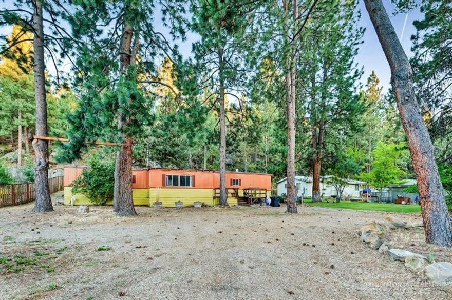 Woodriver Village. What was once a path of progress neighborhood is now the hottest sub-division in Bend! Of course it is because it's nestled against the Deschutes River, the Old Mill, and a short distance to Downtown Bend. There's not a nicer lot in WRV available right now! Keep the manufactured home and rent it until you build your dream home! This nearly acre lot is cozy, quiet & surrounded by Ponderosas and tucked against the hillside & natural vegetation and boulders. A very special place!