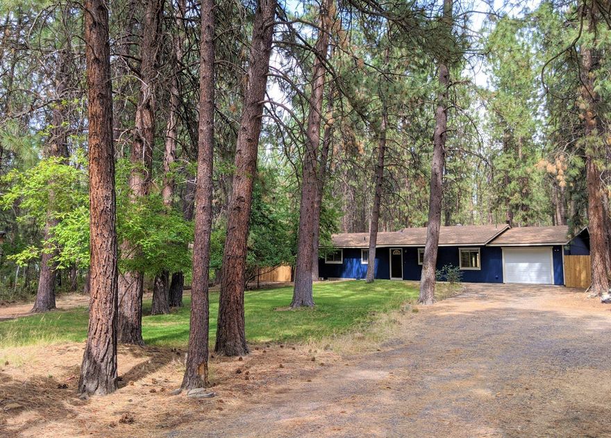 Charming home nestled in a park-like setting with a great location close to outdoor trails, Deschutes River, Mt. Bachelor, and downtown Bend. Centered on .98 acres with Ponderosa and Aspen trees shading velvety lawns perfect for staying cool in the summer and building snowmen in the Winter. Located on a quiet street great for walks in the fresh air while still having quick access to HWY 97. Easy to maintain home boasts natural light throughout, 5 panel doors & wood burning fireplace for cozy winter nights. Updated kitchen appliances, fixtures, counter tops &  new enameled cast iron sink. French doors open to large slate patio with lava rock fire place great for entertaining or enjoying quiet nights next to the fire. Fully fenced backyard is secure for kids, pets or chickens to roam. In addition to a one car garage, a log cabin storage unit makes a great play fort or gardening shed. Endless opportunities for storage of RVs, boats, ATVs. bikes & plenty of room to build new or add-on