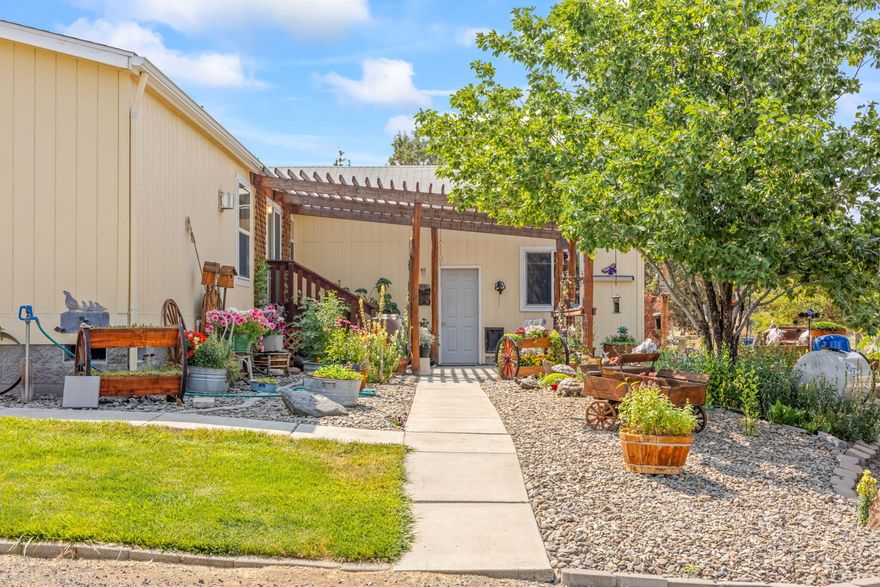 Bring the horses, goats and chickens and homestead on this 2 acres. Fenced and cross fenced and located on paved road. 1856 square foot, 4 bedroom, 2 bath home with double attached garage, barn with 3 stalls, workshop, greenhouse and chicken coup. Home has some updating recently with primary bath walk in shower. 14x20 patio with pergola cover and fun water feature with lily pads and fish. 8x10 front deck and concrete sidewalks front and back. Western front on greenhouse and poultry coup.  3 ton hay storage and attached workshop. Nice small horse set up with corral. Very good producing well-  log reads 40+ GPM. Extraordinarily landscaped with beautiful trees and flowers. Carport for boat or RV. Gated driveway with lots of turn around space and parking area. School bus stops in front of the property. Home is vacant and ready for new occupants.