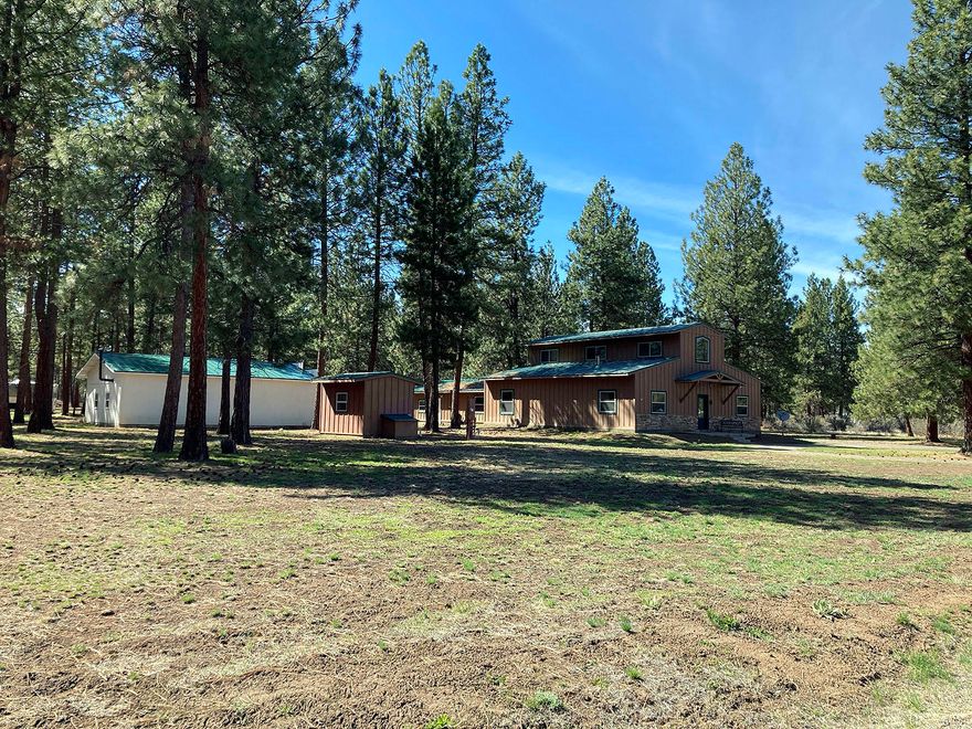 Come see this unique, rustic, quality built home that sits on approx 2 acres in the Pine Meadow Village Ph1 subdivision. House features approx 2376 sq ft, kitchen area, dining room and TV area are all features of this wonderful open plan layout. Large ensuite  master bedroom is located on the main floor including a beautifully finished bathroom with a large closet. Concrete slab flooring throughout the home, painted a gorgeous blue turquoise color finished with a gloss coat, looks uniquely amazing! Tall ceilings with a gorgeous wood staircase that leads upstairs to a 1 bedroom/1 bath and an additional room that is currently used as an office or, could be a 3rd bedroom. Attached garage is Approx 48X48 - 24X24 section of the attached garage is currently used as a recreational room(many opportunities for this room!) The remaining 24X24 is garage space. Also on the property is a large shop(approx 30X40), a covered parking structure and an additional storage/studio building.