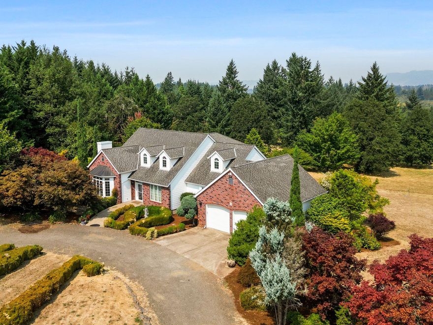 Dream home, property & location! 4-bed, 2.5-bath stunning home on 17+ acres w/irrigation. 3,350 sq.ft., with 2006 sq.ft full daylight basement.  Grand vaulted ceilings, hardwood floors, gas fireplace, and French doors to balcony overlooking beautiful pond & grounds. Spacious kitchen w/island, double ovens, trash compactor, pantry and breakfast nook. Stately library with fireplace and extensive wood finishes with built-in bookshelves.   Formal dining area includes a butler's pantry. Primary suite w/balcony, spa-like ensuite bathroom and two walk-in closets. . Daylight basement, rec room, patio access & storage rooms. Expansive 48'x60' shop, garden shed, 3000 gallon cistern, 10 acres of marketable timber, fruit producing orchard, kitchen garden & mature landscaping.  Large pond for irrigation and for your enjoyment.  Circular, graveled driveway, stone pillar monuments at entrance. Located at end of dead-end street.