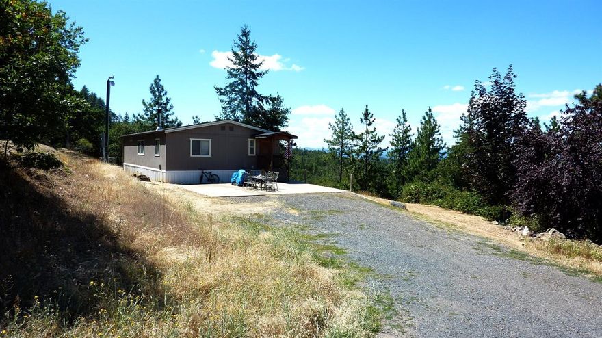 Country Pure and Simple!!!!! Views, Views, and more Amazing Views 5.04 acres of beautiful property to make your own with endless possibilities. The manufactured home has three bedrooms, 2 baths, 1404 Square Feet, large kitchen with lots of cupboards and eating bar, spacious great room, open floor plan with split bedrooms, master bedroom with a double head walk in shower in the master bath, inside laundry, Artesian well per seller, property is terraced with a lower field possibly for horses, garden area has automatic sprinkler system, chicken coop complete with chickens and running water, separate office with electricity, yearly pond, and fully fenced. Bring your hiking shoes and be prepared to explore an awesome property. Call for your personal tour!