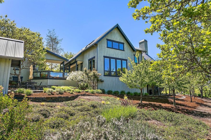Acclaimed builder Clay Colley created quiet elegance and dramas in natural light for this modern country house on wooded 10+ acres steps away from Emigrant Lake and a few minutes' drive to world-class culture in downtown Ashland. Highest caliber craftsmanship shows in features that include alder wood carpentry, geothermal-powered radiant heating in Brazilian slate floors, a hand-stacked stone fireplace, and metal-cladded wooden windows. The kitchen boasts top-of-the-line stainless steel appliances, a large island and an adjoining bar for guests to watch the chef. An airy main-level master suite with a vaulted ceiling adjoins dual bathrooms, spacious walk-in closets, and a deck with a panorama of mountains and valleys. Upstairs are three oversized bedrooms, one with a built-in desk and alder bookcase, all with stunning views. The low maintenance landscaping includes two patio areas suited for seasonal sun and shade, locally quarried stone, flowering trees, and hardy perennials.