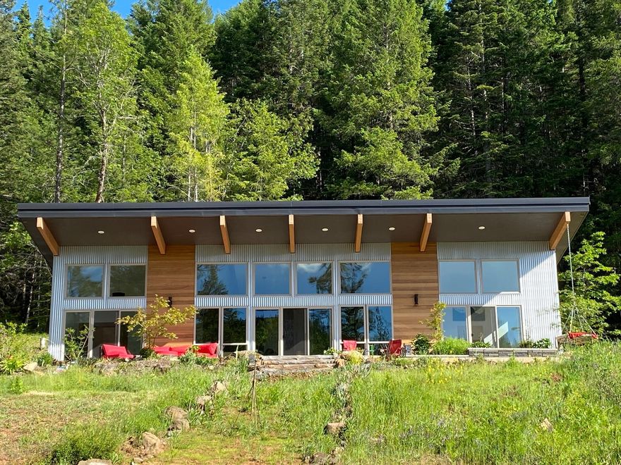 Built in 2021 is this beautiful custom home on 21.77 private acres. Through the gated entrance is this amazing property bordered by BLM and Forestry owned lands. Featuring 3 bd, 2-1/2 ba, split floor plan, open beams with 15' ceilings, wood stove and floor to ceiling picture windows to admire the views. Interior boasts hardwood and tile flooring, custom tile on fireplace and walk in showers, German bathroom accessories and heated floors.  Kitchen with smart hub is well appointed with Bosch appliances, cabinetry with slide outs and outlets, double ovens and pantry. Finished studio or guest quarters with ½ bath, wood stove, laundry hookups and outside shower. 18x6 swim spa with sun deck and RV storage with full hook ups. Fenced garden area with irrigation, green house, fruit trees, aviary and pens surround Chapman Creek that runs through the property. This land has hiking, biking, horse and ATV trails. Did I mention the marketable timber? Endless opportunities at the Rusty Peacock Ranch.