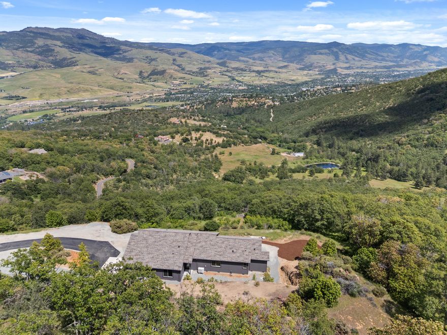 Luxury meets efficiency & privacy in this 2025 custom home, designed to capture truly stunning panoramic valley views. Earth Advantage Platinum certification guarantees a healthier & more comfortable living experience, provides peace of mind through the use of sustainable & durable products, and saves thousands. Set on a private 5-acre lot with ample parking. The breathtaking views are brought in through transom windows & sliding French doors in the vaulted great room, complete with a cozy electric fire feature. The kitchen is both stylish & functional, featuring a center island, walk-in pantry, textured quartz countertops, and artisan tile backsplash. White oak wood flooring throughout with tile in the bathrooms. Private well + holding tank & filtration. Paved drive to the house. Ready to be elevated with your vision for landscaping and outdoor living. XL 2-car garage with workshop space. Only 10 minutes from downtown. Built by Suncrest Homes, trusted builder of over 450 local homes.