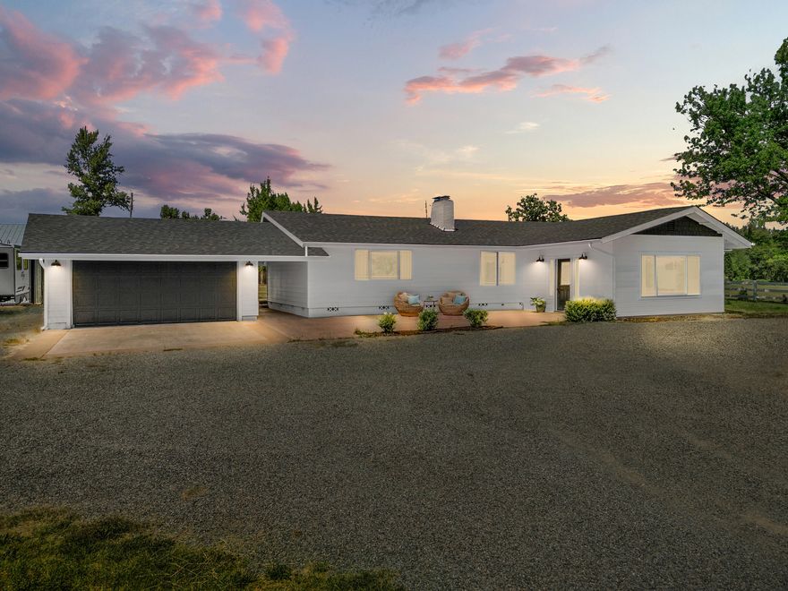 Set atop a gentle knoll in one of Josephine County's most coveted neighborhoods, this truly special property offers the kind of lifestyle people dream about. With 6.17 irrigated, fully usable acres, this single-level ranch brings together craftsmanship and comfort thanks to the panoramic views of the Cascades, natural slate and black oak floors, knotty alder doors, and a show-stopping 9' redwood slab island in a chef's kitchen made for gathering. The primary suite is a retreat of its own with a cozy gas fireplace and a spa-like dual-head shower. Step outside to a peaceful country setting with fenced pasture, a pond, raised beds, 20x40 shop, and space for everything from hobby farming to backyard baseball games. The kids have their play yard, you'll have your sunsets! Just about everything has been updated: new roof, HVAC, paint, plumbing, electrical, and more. This is more than a home—it's a lifestyle, and properties like this don't come around often.