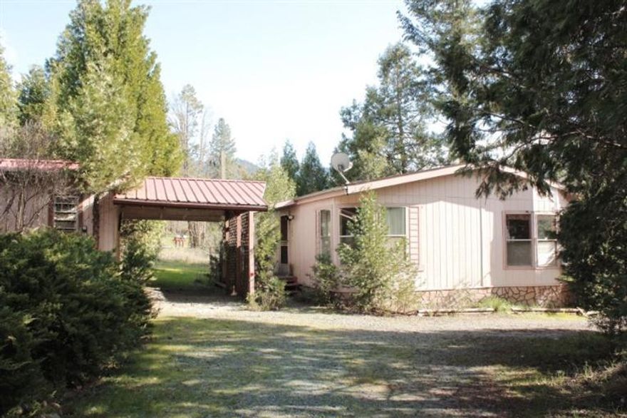 Golden Opportunity to own your own home on a half acre at an affordable price! This gem is privately set on a level, partially wooded and partly open .51 acre parcel in a great location near the river and close to both Grants Pass and Rogue River! The 2 bedroom home is a 1991 double wide manufactured home with a covered front porch and an enclosed back porch and features a Great Room with vaulted ceiling, dining area and open kitchen with laminate flooring, 2 carpeted bedrooms and 1 1/2 bathrooms. The property sets off a paved public road, has a circle gravel driveway, carport, several storage sheds, a garden area with Iris' popping up for spring! There is also a separate open area large enough for an RV, big truck or extra vehicles. Call today for more details!