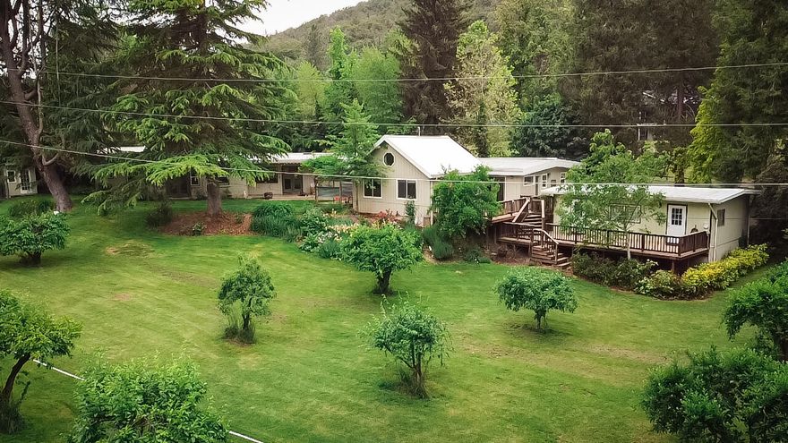 Searching for Privacy? You found it with this single-level, Mid-Century charmer on 1.54 acres with irrigation and Griffin Creek frontage. Conveniently located between Jacksonville and Medford, while still offering a serene country setting. Not only do you get a 3-bedroom, 3 bath house, but also a 1 bedroom, 1 bath with full kitchen cottage/ADU. Open-beam ceiling and hardwood floors in the cottage. The main home has hardwood flooring in the dining room and living room and floor-to-ceiling windows to enjoy the peacefulness of your surroundings. Updated kitchen and bathrooms sure to please. Also, there is a bonus room with vaulted ceilings that would make a wonderful bedroom or family room. The carport has enclosed storage and an 18X9 room perfect for an office or guest room. 20X20 shop, firepit by the creek, garden, and personal orchard w/apple, fig, pear, cherry and plum trees. You just can not find a more perfect place to call home. Get your appointment set to tour today.