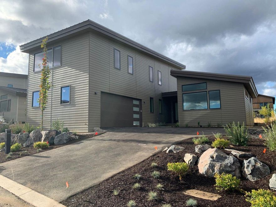 A beautiful contemporary design by BendTrend Homes in the Trailhead community of Tetherow. This home features a 3,262 sf two-level floor plan with primary suite, mud/laundry and large den on the main level. There are two additional hybrid en-suite bedrooms and a bonus room upstairs. Luxury finishes and craftsmanship throughout include hardwoods, quartz counters, high-end JennAir appliances, fully tiled showers and floors in all bathrooms, stylish fixturing and Sonos system as standard. The homesite opens to an inviting common area green space. Direct access to Phil's Trail system for mountain biking and hiking just our your back door from this enclave of 28 homes across from the Tetherow pool, fitness center, dining, and golf course. Photos are of other completed homes but represent standard finishes and floor plan. Please see attached document for selected interior finishes.  Under construction with estimated completion end of May 2023.