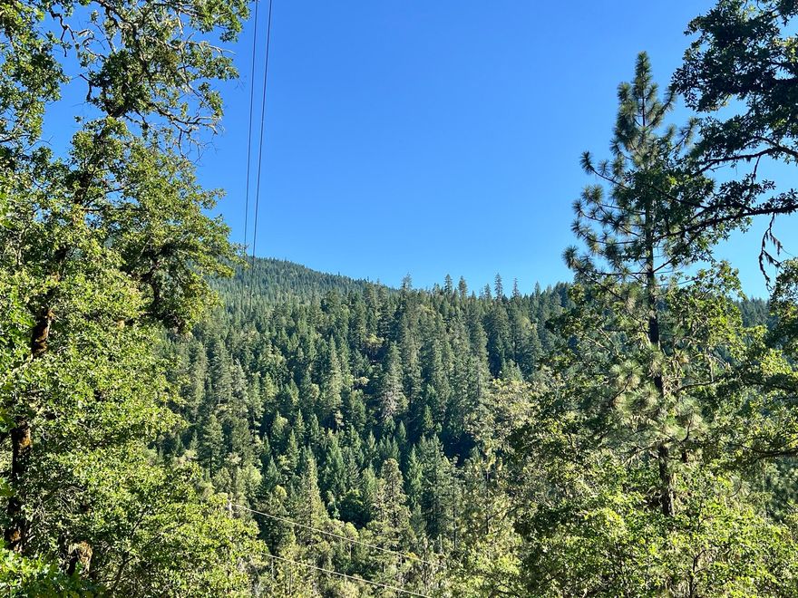 Priced to sell! Over 7.35 acres in Sunny Valley, zoned FC with seasonal creekâ€”ideal for agriculture or future build. Already equipped with a well and septic, the site had a prior 580sf guest studio w/deck & storage shed (structure lost to house fire; mobile remaining on top bench). Stunning valley & mountain views, with excellent southern exposure for crops or recreation. Close to main road but privately nestled against BLM land, offering ultimate seclusion. There is a designated build site if you choose to construct your dream home, and a second bench site for a build. The land also has potential for marketable timber. Perfect for outdoor activities - hiking, fishing, or dirt biking. Use your imaginationâ€”this property provides a blank canvas for farming, recreation, or private retreat with existing water source. Buyers should perform their own due diligence regarding zoning, uses, and timber value. This is a rare opportunity for versatile land with incredible views and privacy!