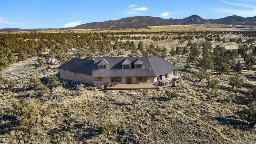 Perched above the high desert landscape on 40 acres, this property offers privacy and sweeping 360° views just 25 minutes from Bend. Designed to embrace its surroundings, the home features 41 expansive windows capturing panoramic vistas: from sunrise over Powell Butte to sunset across the Cascades. A private drive with two gated entrances leads to the home's modern floor plan with a main-level primary suite, an expansive great room, a three-car garage with EV charging, and speedy Starlink internet. The back deck becomes an outdoor oasis, complete with a sauna and hot tub positioned for evening alpenglow and stargazing. A versatile outbuilding supports equestrian or recreational use, while the fire pit, RV hookup, and classic Airstream (also for sale) elevate the outdoor experience. A one-of-a-kind retreat defined by sweeping views, exceptional privacy and a direct gateway to thousands of acres of public land that shape Central Oregon's outdoor lifestyle.