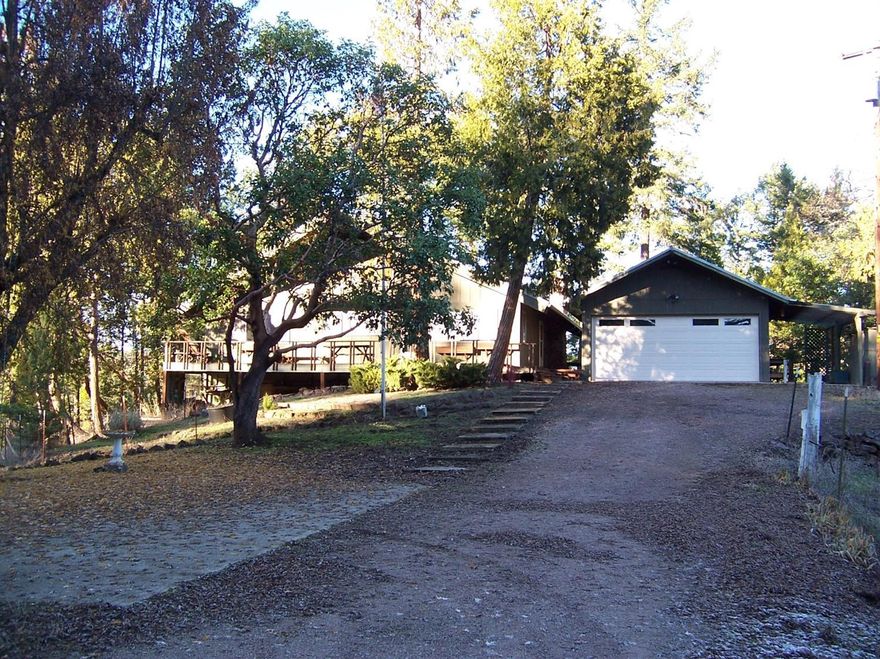 Check out this nicely updated 3 bedroom, 3 bath home, situated on a beautiful & very peaceful wooded site with 6.10 acres of very usable land & nice views. This 2 story home features a large open kitchen W/slate flooring, huge great room with gorgeous 18' open beam ceilings, W/certified Blaze King wood stove & beautiful stone hearth. Enjoy the wall of windows w/access to large deck area overlooking this tranquil private setting. Lower level also includes the Master bedroom & bath, guest bedroom & guest bathroom, walk-in pantry & utility room. Upper level included: Bonus room/office that overlooks the Great Room, additional guest bedroom with in-suite bathroom. There's lots of additional attic storage too. Good well per owner, plus holding tank. Outside features include: Lots of parking, small barn/shop, 2 car detached garage, carport & covered firewood shed. Plus a 1 bed/1 bath guest unit (240 sq) located at the back of the garage. All of this is just a few minutes to Shady Cove.