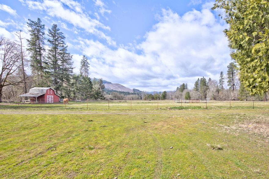 Gorgeous nearly 20 acres of Applegate river bottom pasture, with 15 acres irrigable.  This sweet home is set right on the river, but above flood level of 1997. Seller believes the light and open porch/family room is additional to the county assessor's square footage.  Views of the valley are sumptuous, and the location is end-of-the road private.  Garage is single car, detached, and there is a classic mini-barn located at the edge of the pasture.