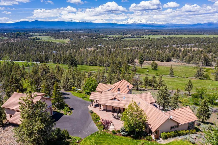 Tucked back, up a long paved driveway, this immaculate home rests on over 21 acres with unbeatable Cascade Mountain views spanning from Mt. Bachelor to Mt. Hood. Enjoy the view from almost every room or on the large West facing deck with hot tub surrounded by mature trees + additional paver patio with fireplace. Completely remodeled in 2006. Brazilian cherry wood floors, Mexican Saltillo tiles in the kitchen, granite counters in the Chef's kitchen with copper farm sink & walk-in pantry. Great room with extraordinaire gas fireplace plus wet bar complete w/ beverage cooler & soapstone counters. Tulikivi soapstone wood burning fireplace/pizza oven, formal dining w/ walnut built-in cabinets. Master suite has 2 walk-in closets, two vanities, tile shower plus sitting area, gas fireplace & access to the hot tub. 2-car garage with guest suite + full bath above, barn with additional guest suite, large pole building w/ 3 RV doors, 2 ponds fed by 7.7 acres inground automatic Tumalo irrigation.