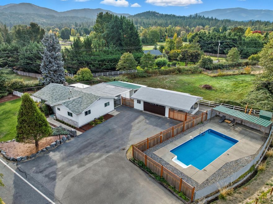 Pride and Joy of Ownership for this Single-Level Home on Nearly 1 Acre with Pool, Shop, and pasture. Inside, you'll find fresh carpet in the inviting living room, complete with a cozy wood-burning fireplace, and a functional galley kitchen perfect for home-cooked meals. Enjoy summer days by the in-ground heated pool, or take advantage of the pasture with irrigation access, which conveniently separates the living space from the pastured area. The property also includes a shop, multiple storage rooms, and a massive finished two-car garage ideal for projects, vehicles, or hobbies. New gates provide numerous access points to covered areas and storage, offering flexibility for equipment or recreation. This property offers rural tranquility with modern conveniences ready for you to make it your own!