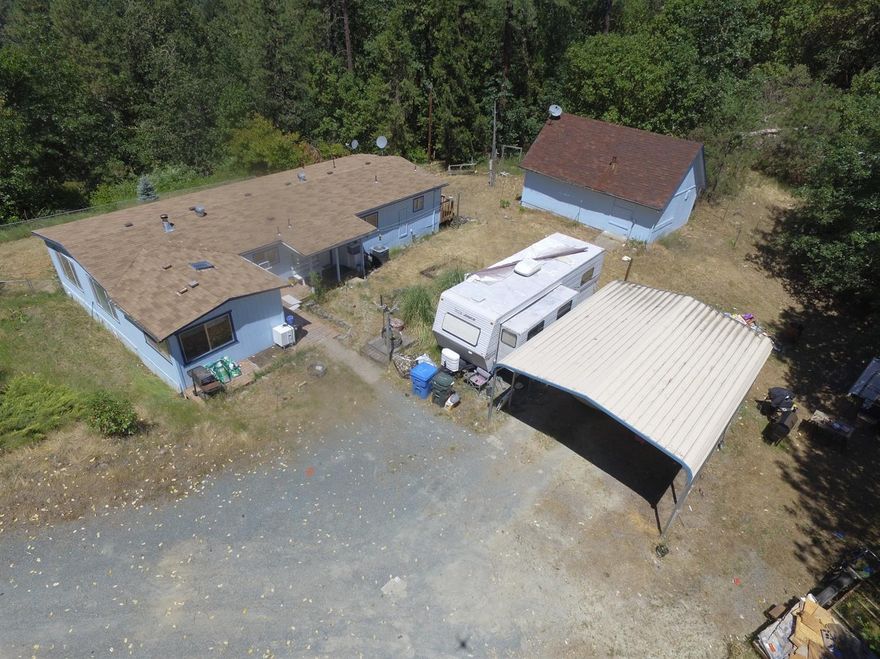 Charming 3 bedroom possibly a 4th bedroom/craft room/office/den, 2 bath 1600 sq. ft. home surrounded by trees with beautiful views of the mountains. Roomy kitchen with plenty of storage space. Large windows brighten up the living room, w/ceiling fans, double paned windows and window treatments. Located on 1.51 acres there is a partially fenced yard, a nice sized outbuilding for extra storage space. This is a large covered carport and plenty of room outside to garden or entertain. The workshop is 2 story and appro. 28X16 and there is also ample room for an RV with RV/septic pump hook-ups. Also there is 2 individual carports. The largest is 8 ft. 20 X 26 . This is a must see! All information deemed accurate but not guaranteed and subject to change at any time.