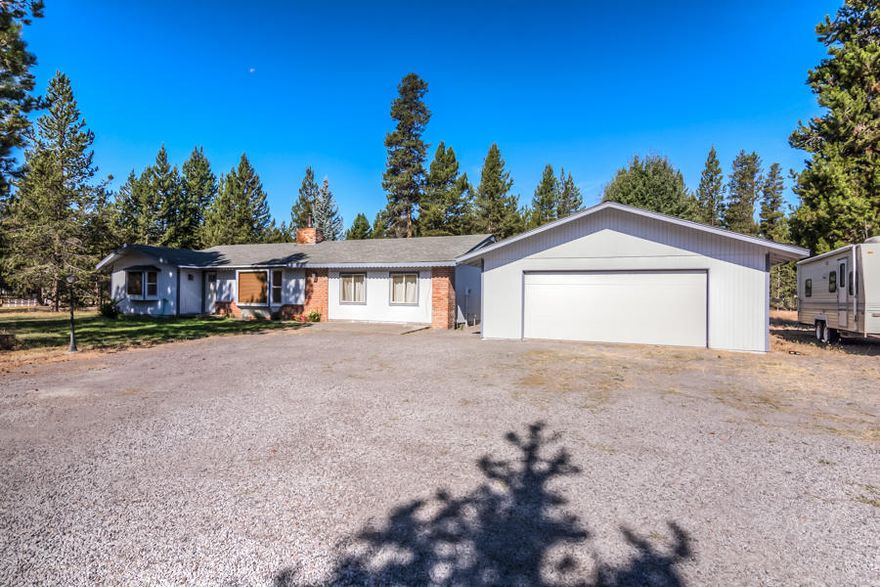 Located just off of Day Road in La Pine, this stick built 3 Bedroom, 2 Bath, single level home offers more than expected.
Set back from the road and on a one acre corner lot, this home provides privacy and space without sacrificing location. Settle into the sunken living room where large windows provide plenty of natural daylight and a brick mantle perfect for a new wood or pellet stove.  Walk through to the kitchen outfitted with freshly painted cabinets, brick accents and a sliding glass door to the covered patio and backyard.  The master bathroom has been updated with new vanity, flooring and tub/shower.  Home is complete with a large detached 2 car garage/shop, a storage shed and a heated, insulated and plumbed bunkhouse ready for guests or as a potential rental.