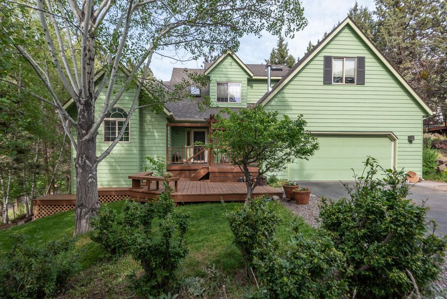 This lovely home on 1/2 acre in NE Bend is tucked back from the cul de sac with mature trees and an expansive deck creating an outdoor paradise simply not found in the newer neighborhoods. Inside, enjoy a large primary suite on the main floor with a new shower, large jetted tub & two walk-in closets. The fireplace is the centerpiece between the living room & dining area, creating both warmth and flow between the rooms. The pristine kitchen has newly painted white cabinetry, gas stove and built-in desk. Upstairs, a loft area is perfect for a home office or homework space. Two bedrooms share a full bath. The finished attic is currently used as an art studio, but could also be a den, second office, play space, or one could use the completed architectural plans to build out an ADU with exterior stairs. A new roof was recently installed. The charm of this property extends from the curb appeal to the unique nuances of the home to the private outdoor living experience.